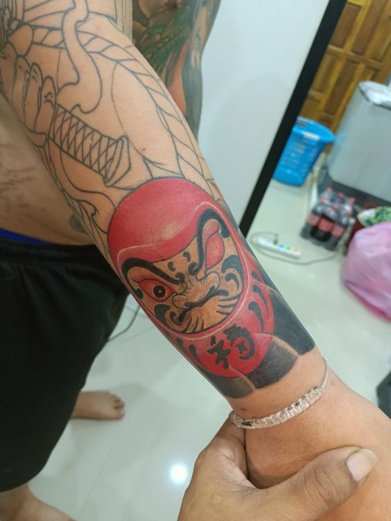 xăm búp bê daruma đỏ ở tay cho khách