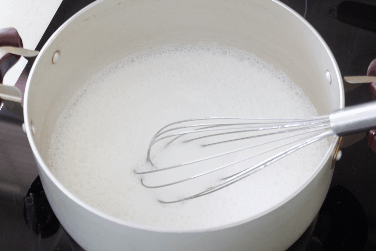 Coconut cream in a pot with a whisk.