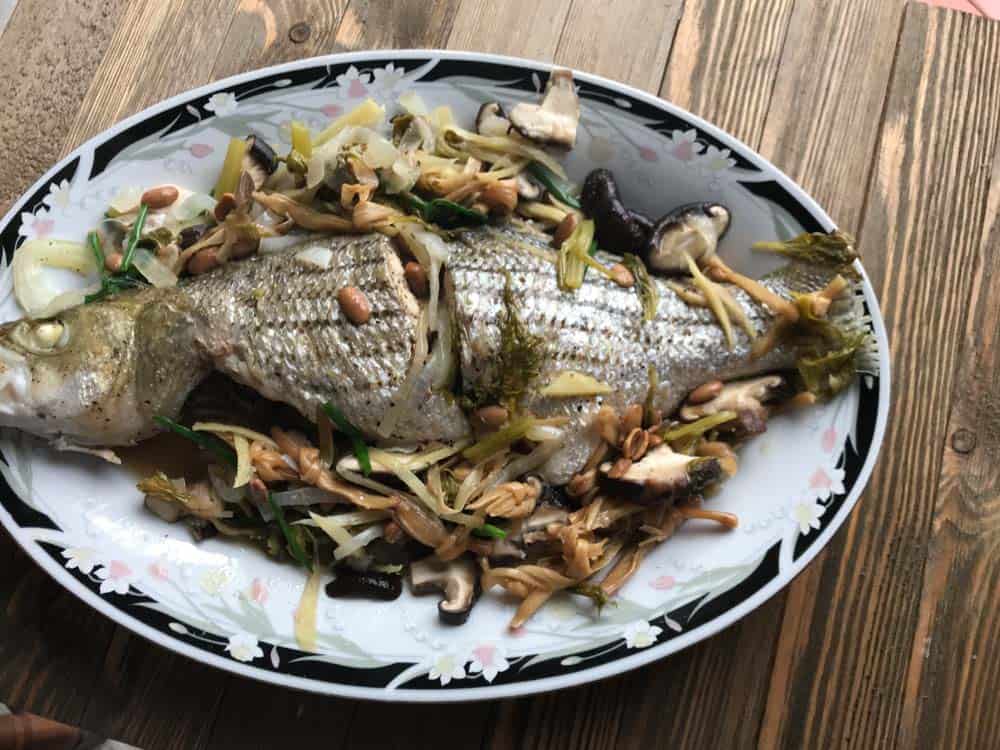 authentic vietnamese steamed whole fish with scallions, mushrooms, bamboo, onions