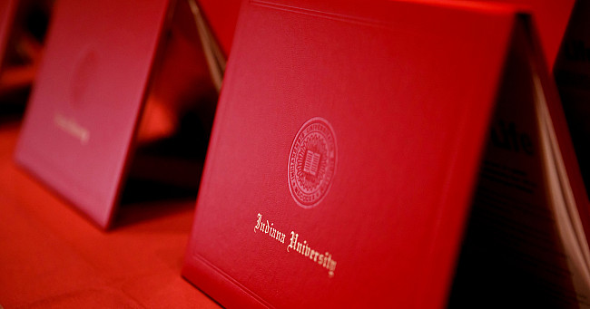 A row of red IU diploma covers